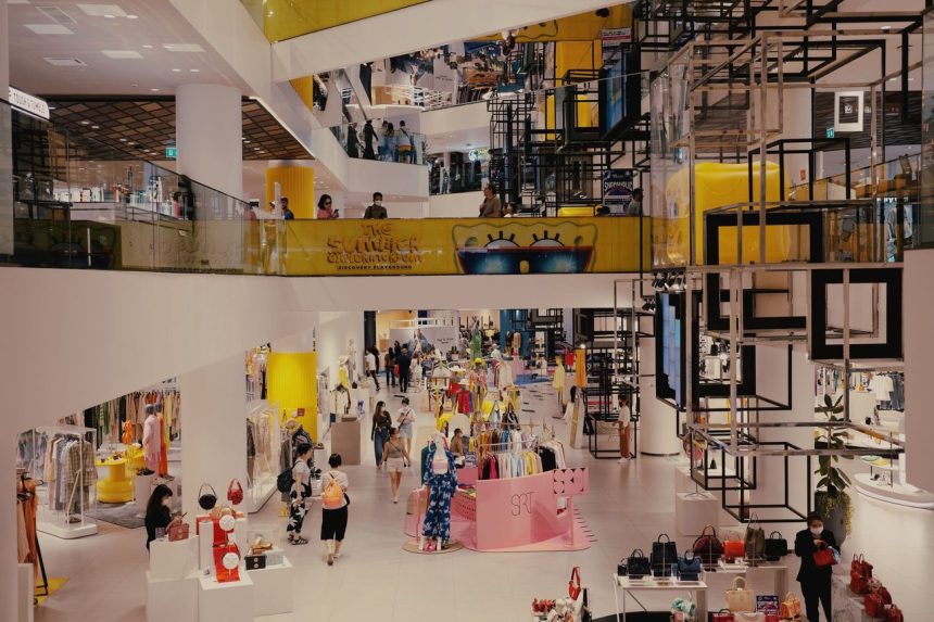 Shopping movimentado, com consumidores circulando entre lojas de varejo em um ambiente contemporâneo.