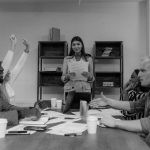 Grupo diversificado de profissionais participa de uma reunião de negócios, discutindo ideias em torno de uma mesa.