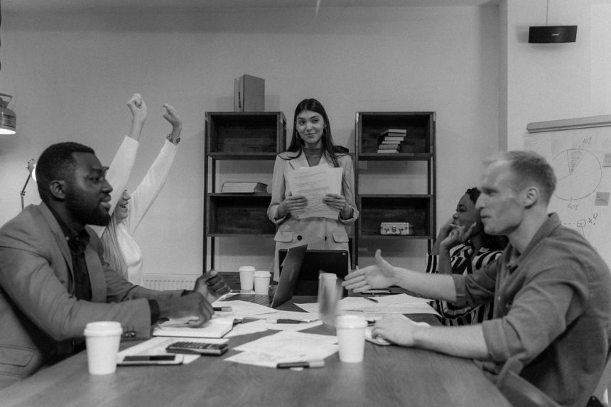 Grupo diversificado de profissionais participa de uma reunião de negócios, discutindo ideias em torno de uma mesa.