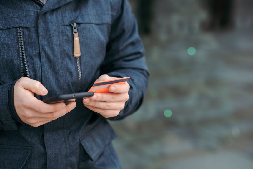 Pessoa usa um smartphone para inserir dados de cartão durante uma compra online.